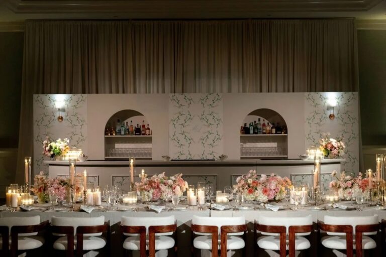 Long table with pink florals and candles in front of a painted bar, About Details Details