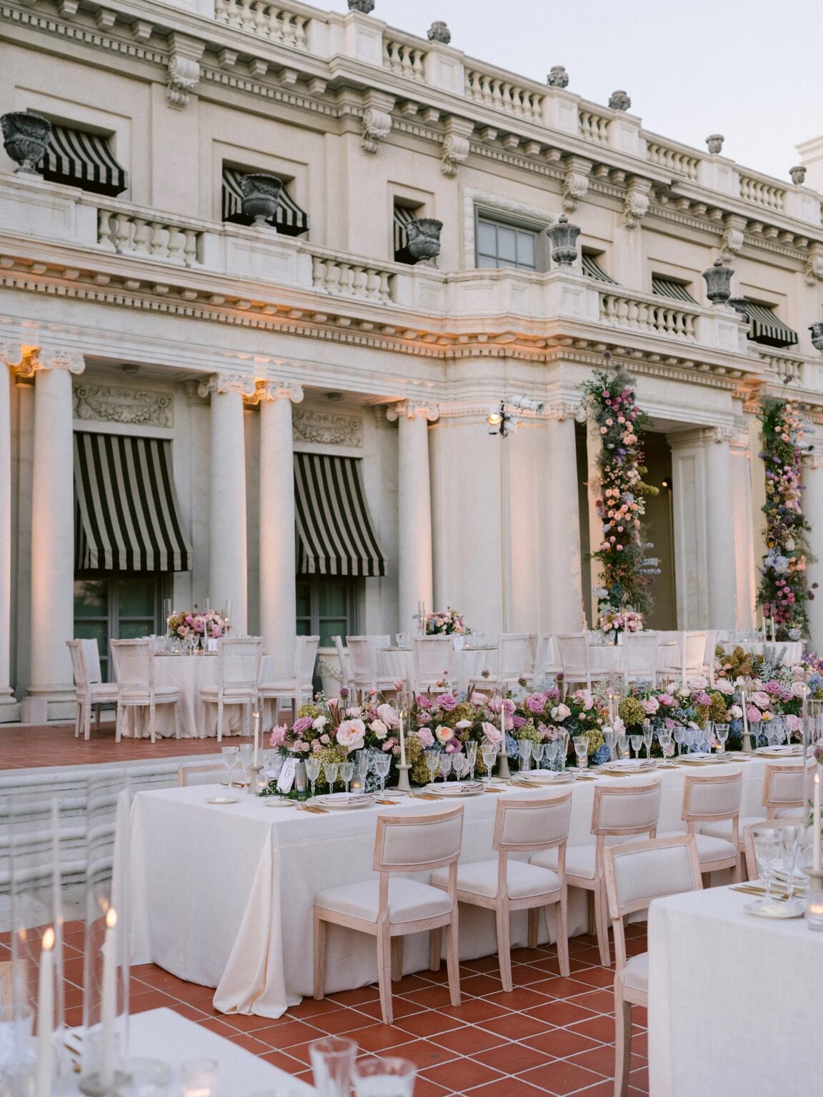 Terrace banquet table with pastel flowers at a grand stone building, About Details Details