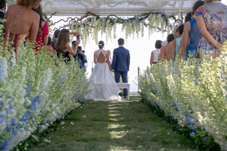 Ceremony aisle between blue and white delphiniums beneath a floral canopy, with the sea beyond (Capri view garden), Alba Greco