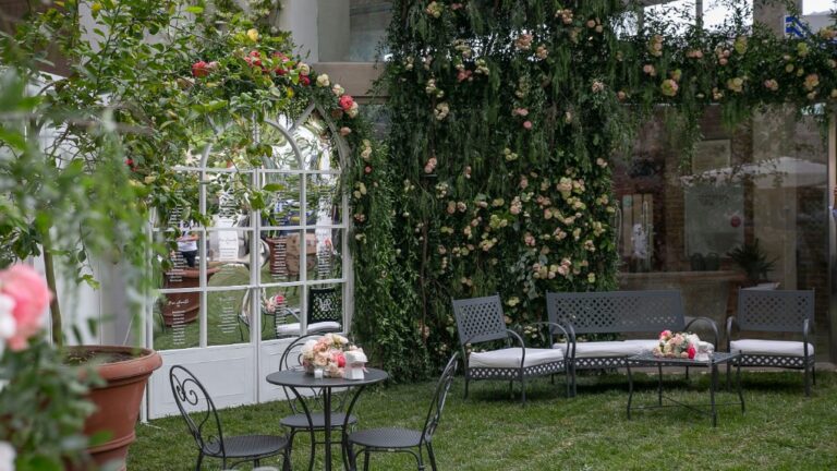 Garden terrace with a white glasshouse and roses in May, Alba Greco