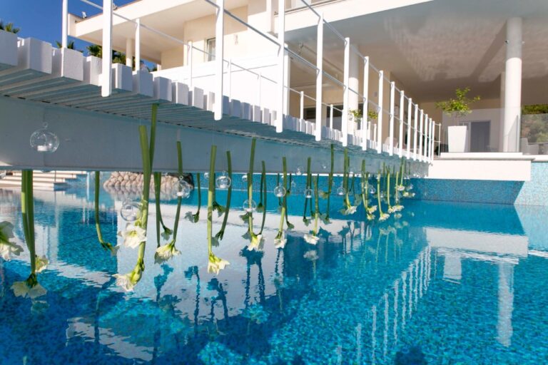 Poolside installation of tall stems reflected in the water at Villa Eliana, Alba Greco