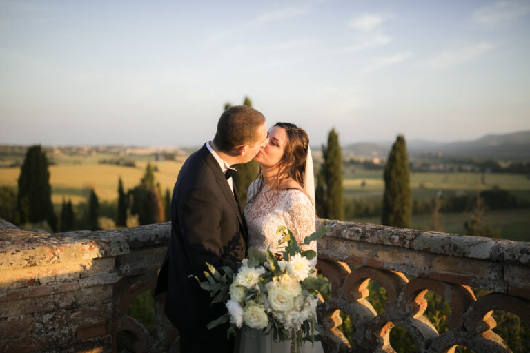 Couple kissing on a stone balustrade above the Umbrian countryside at golden hour, Alessandro Mari Photography