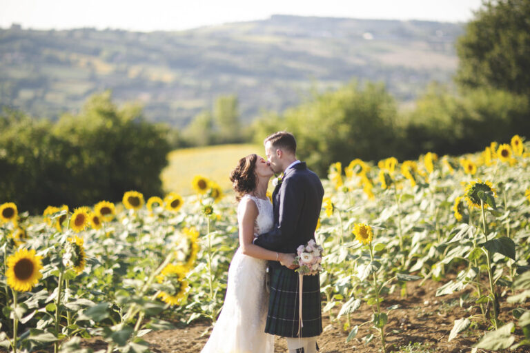 Couple kissing in a sunflower field, the groom in a kilt, Alessandro Mari Photography