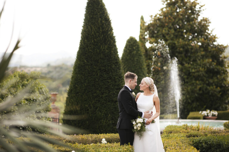 Couple by a clipped topiary garden and fountain, Alessandro Mari Photography