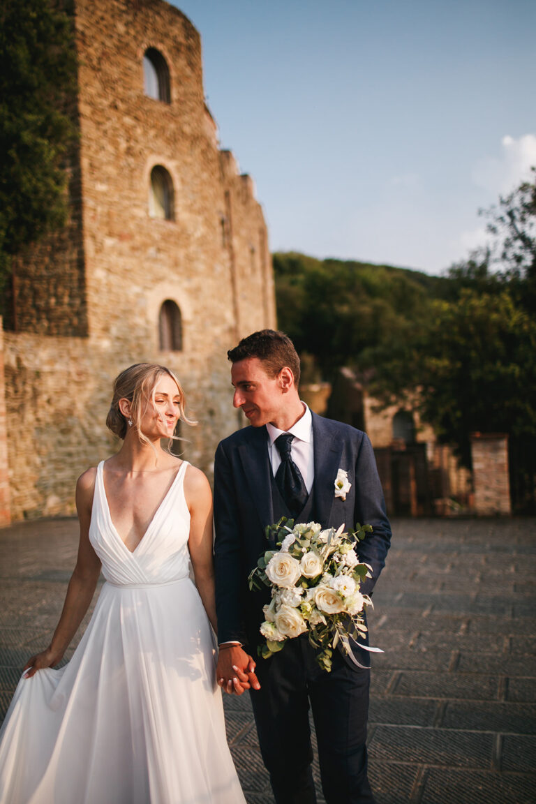 Bride and groom walking in front of a medieval tower, Alessandro Mari Photography