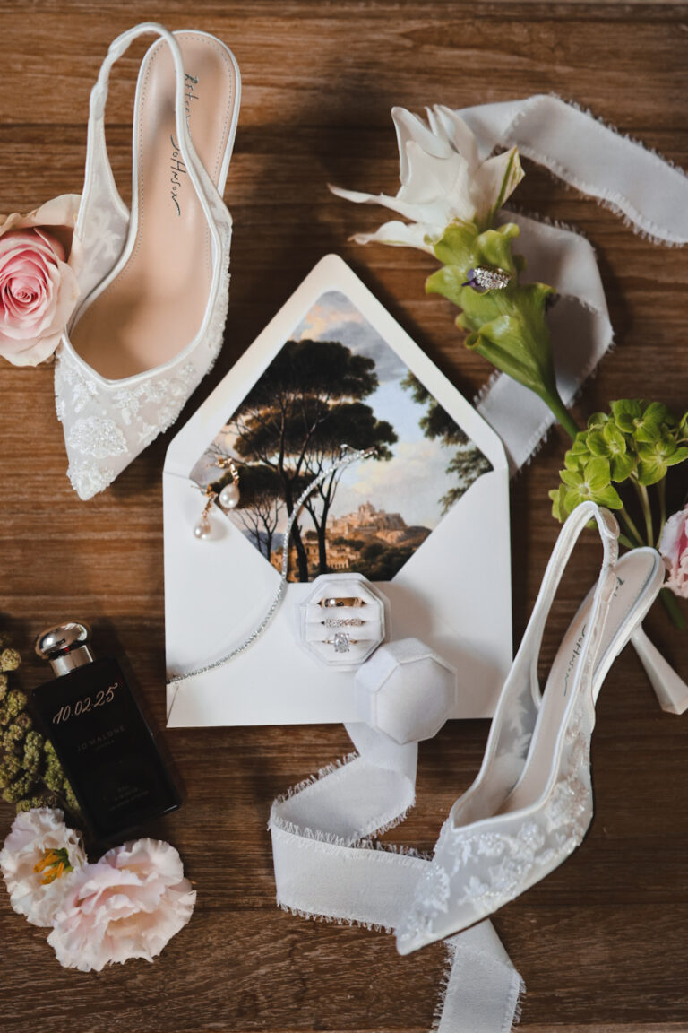 Wedding stationery, shoes and ribbons laid out on a wooden table, Alessandro Mari Photography