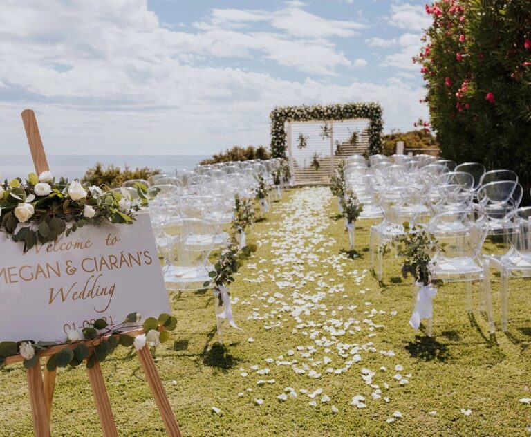Ceremony set up on a lawn with a welcome sign and floral arch, Algarve Wedding Planners