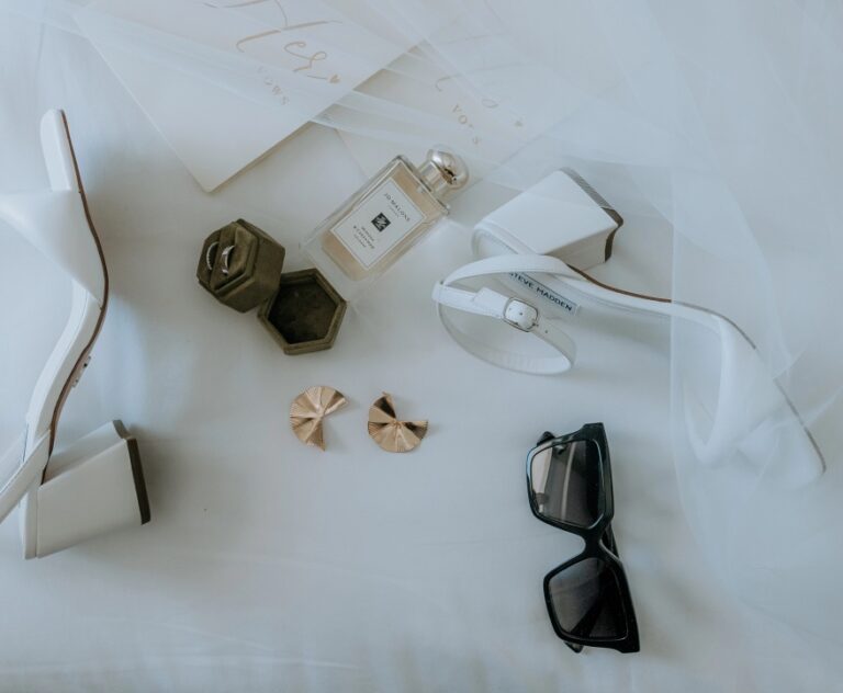 Wedding stationery, rings and accessories laid out on white linen, Algarve Wedding Planners