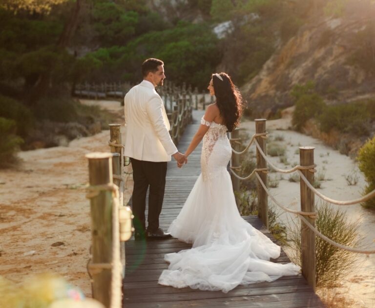 Couple holding hands on a timber boardwalk through dunes, Algarve Wedding Planners