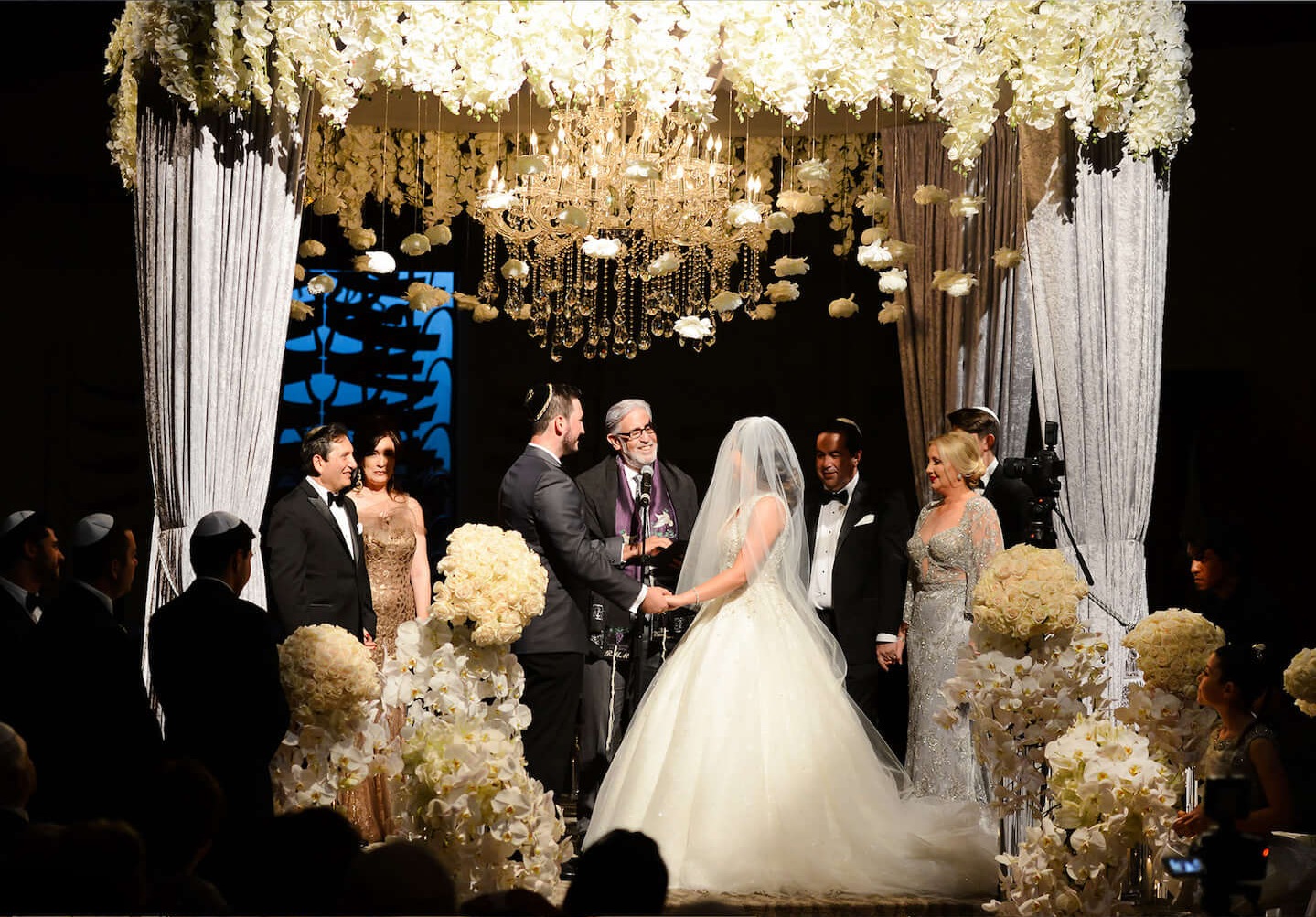 Ceremony beneath a canopy of white orchids and chandeliers with crystal curtains, Aliana Events