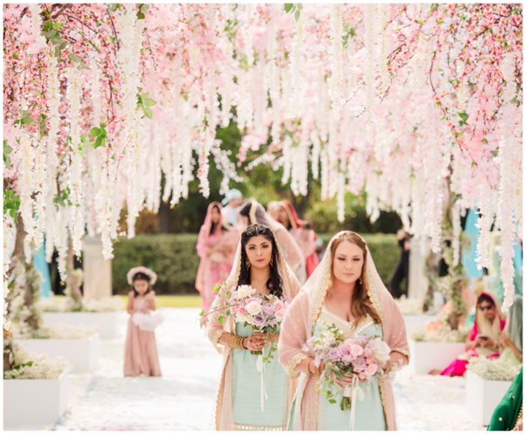 Procession beneath a canopy of pink blossom and hanging white flowers, Aliana Events