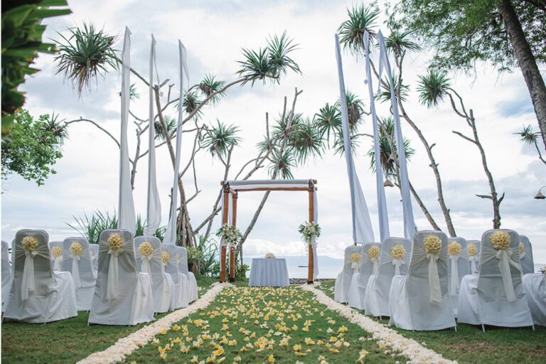 A ceremony aisle strewn with petals under a wooden arch, Alila Manggis