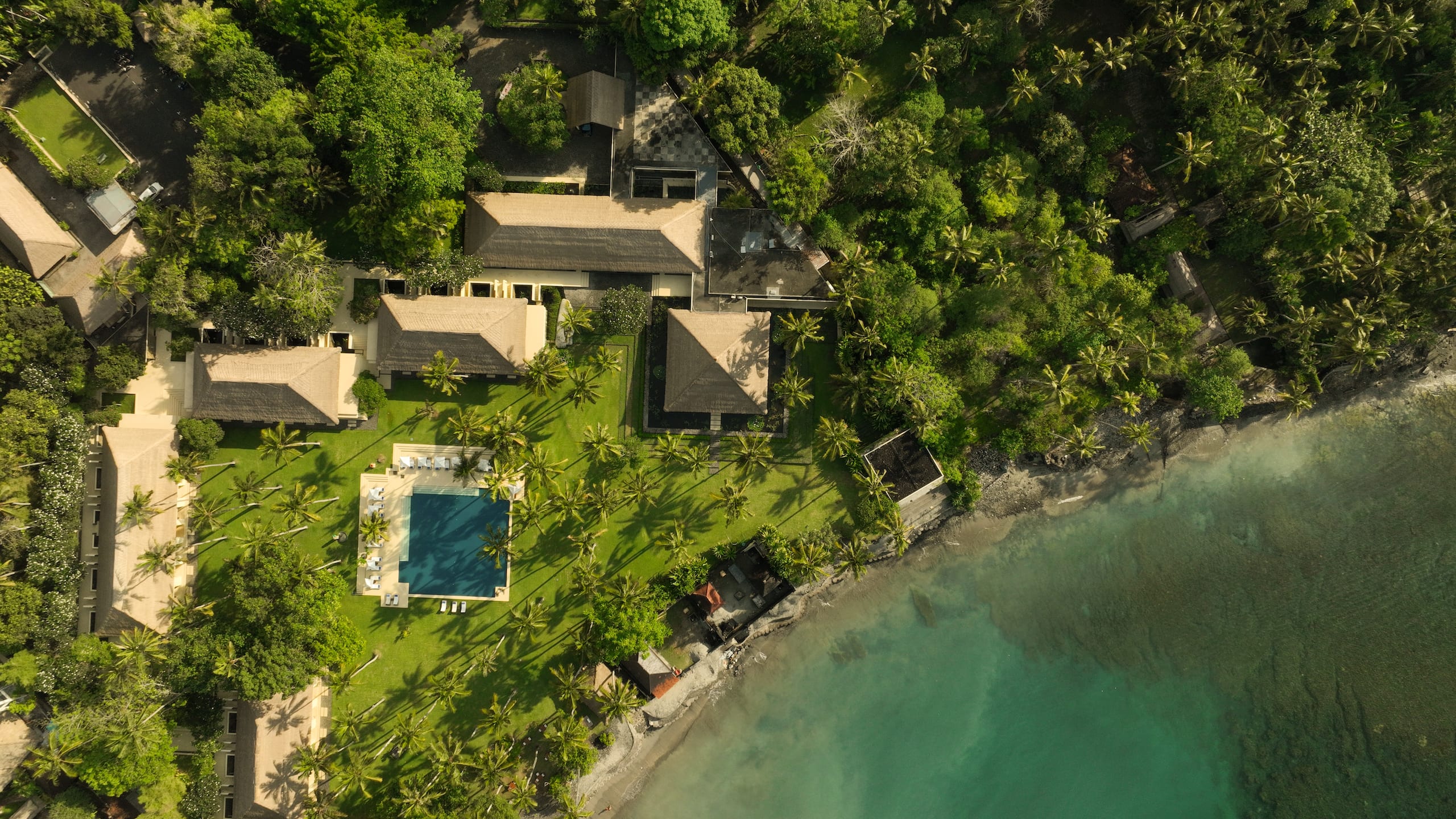 The pool and lawns among the coconut palms, with the sea beyond, Alila Manggis
