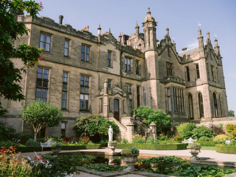 The castle from the garden, its Gothic towers rising above statues and lawns, Allerton Castle