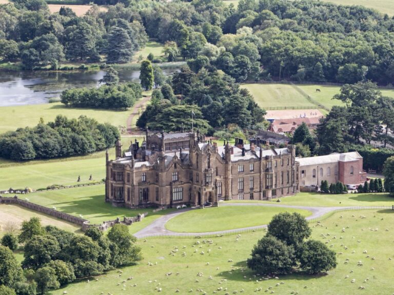 The castle set in green parkland and woodland, seen from the air, Allerton Castle