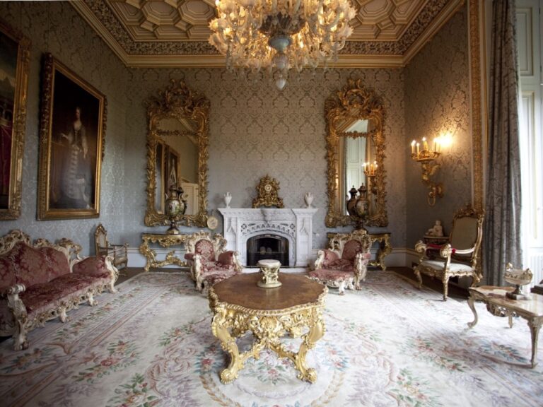 A gilded reception room with a carved fireplace and gold-framed portraits, Allerton Castle