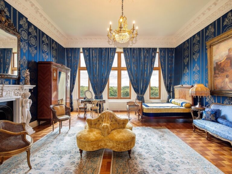 A drawing room in deep blue, with a gilded sofa, marble fireplace and chandelier, Allerton Castle