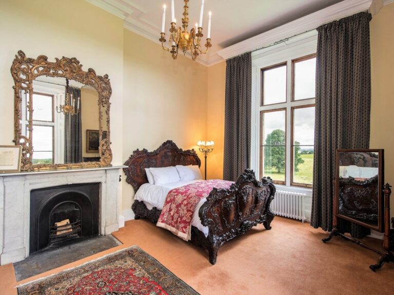 A bedroom with a carved bed, marble fireplace and gilt mirror, Allerton Castle