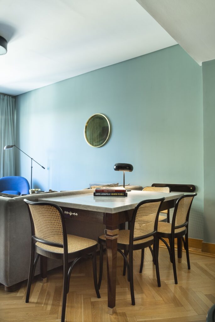 Dining table with cane chairs against a pale green wall, Alvear Design Guest House