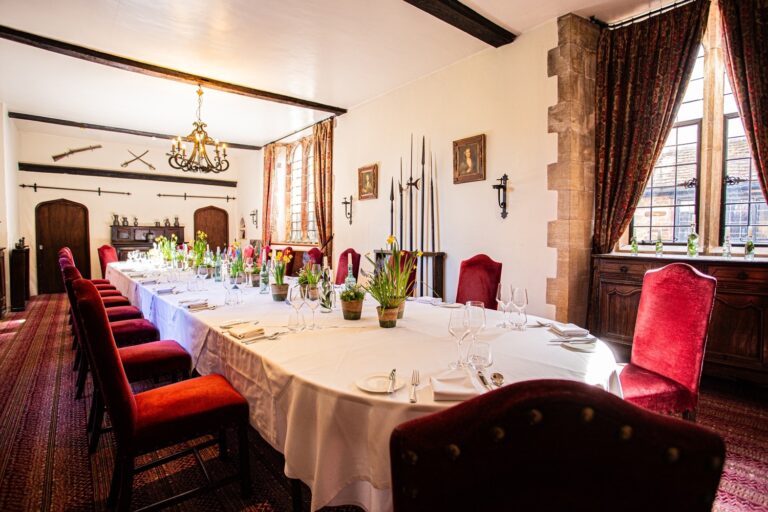 A private dining room set with a long banquet table, antique arms displayed on the walls, Amberley Castle