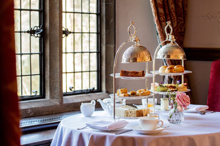 Afternoon tea served on a silver stand beside a gothic leaded window, Amberley Castle