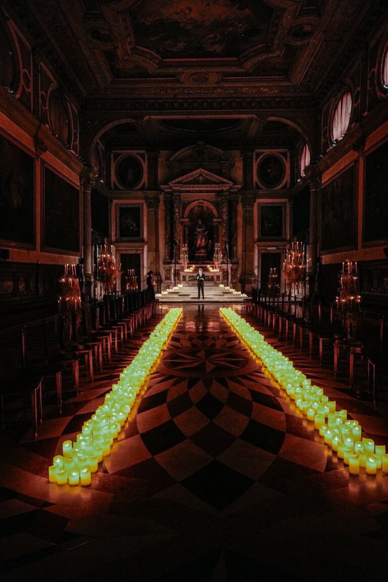 A gilded coffered ceiling and twin runs of green votives converging on the altar, Angel Lion Weddings and Events