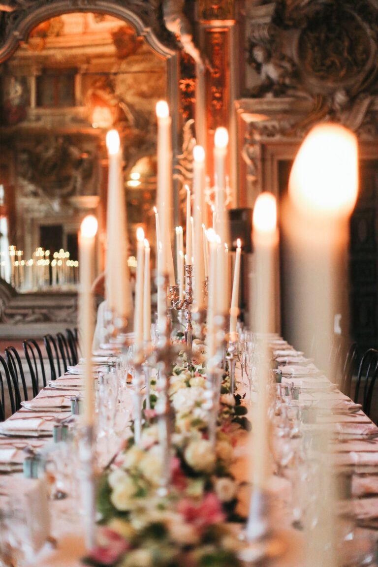 Tall tapers down a long table, low roses between them, Angel Lion Weddings and Events