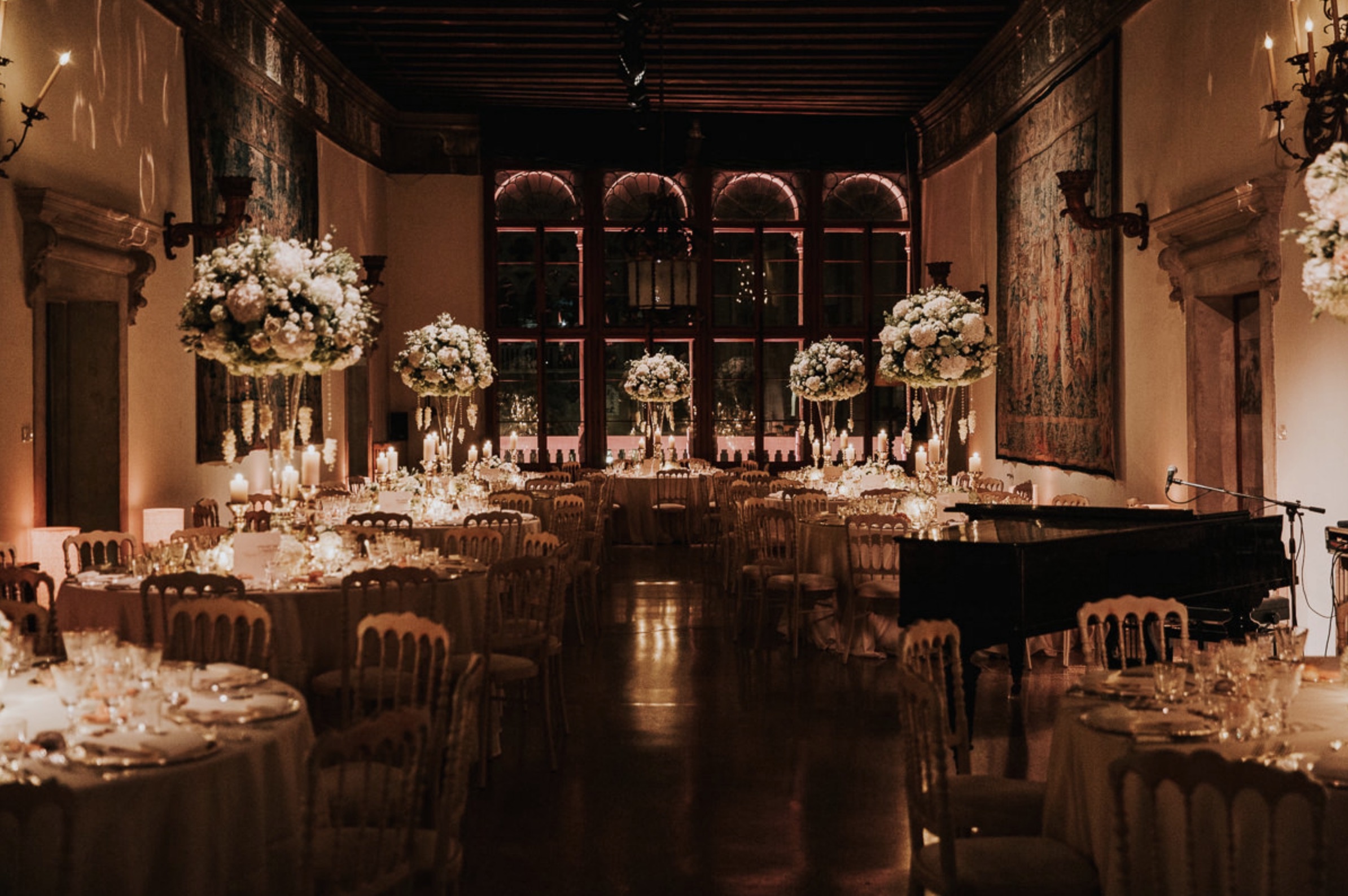A great hall dressed for dinner, a grand piano at the far end, Angel Lion Weddings and Events