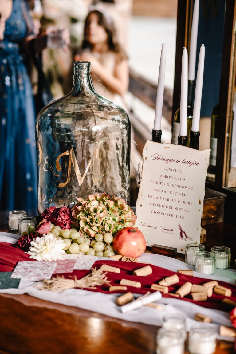 A table with glass demijohn, place cards and fruit, Angela Salzano