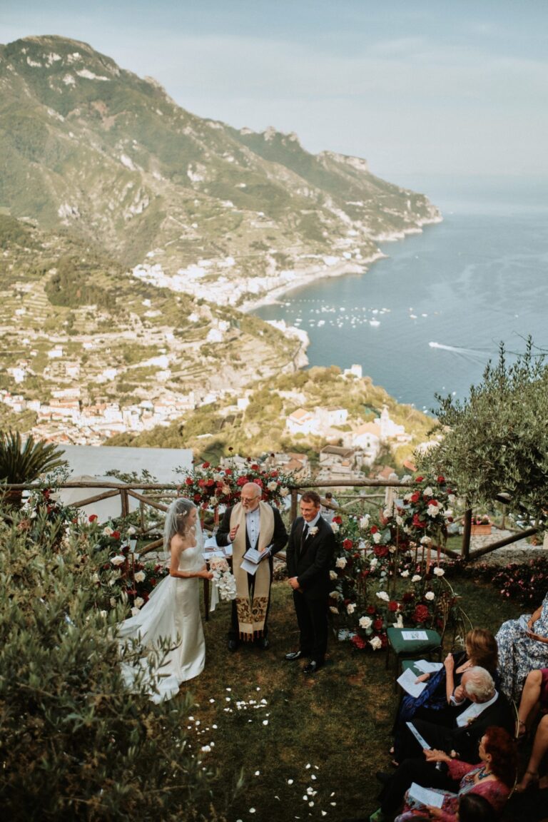 A clifftop ceremony above a coast, the town and the bay spread out far below, Anita Galafate