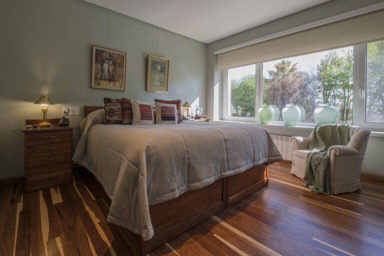 Bedroom with timber floor and a wide window onto the garden, Antucura Wine Estate