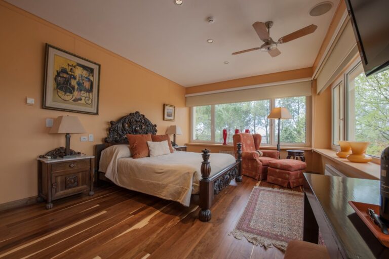 Suite with a carved headboard and timber floor, Antucura Wine Estate