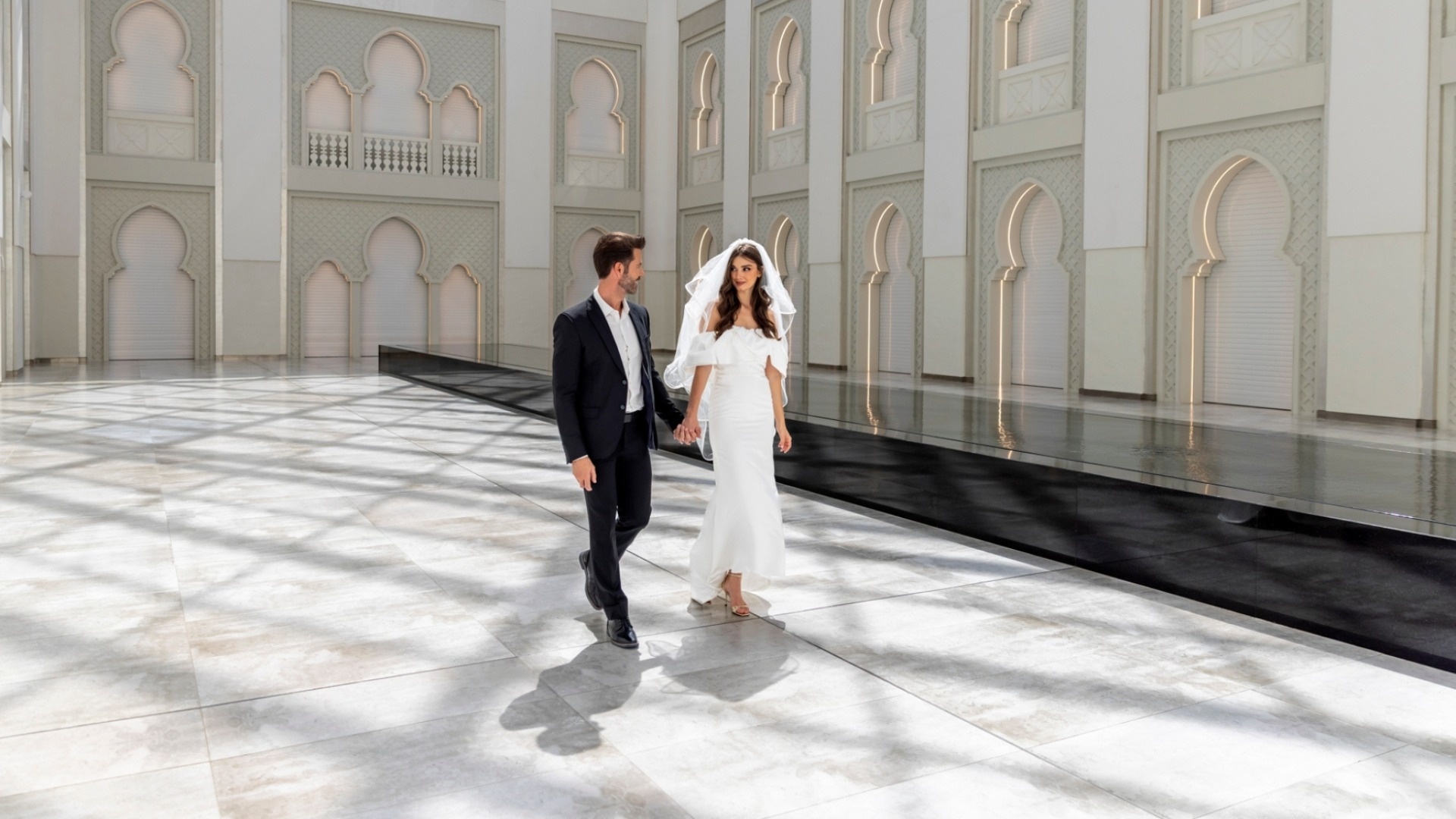 A couple walking across the Skylight floor beneath the arched walls, Arjaan by Rotana Dubai Media City