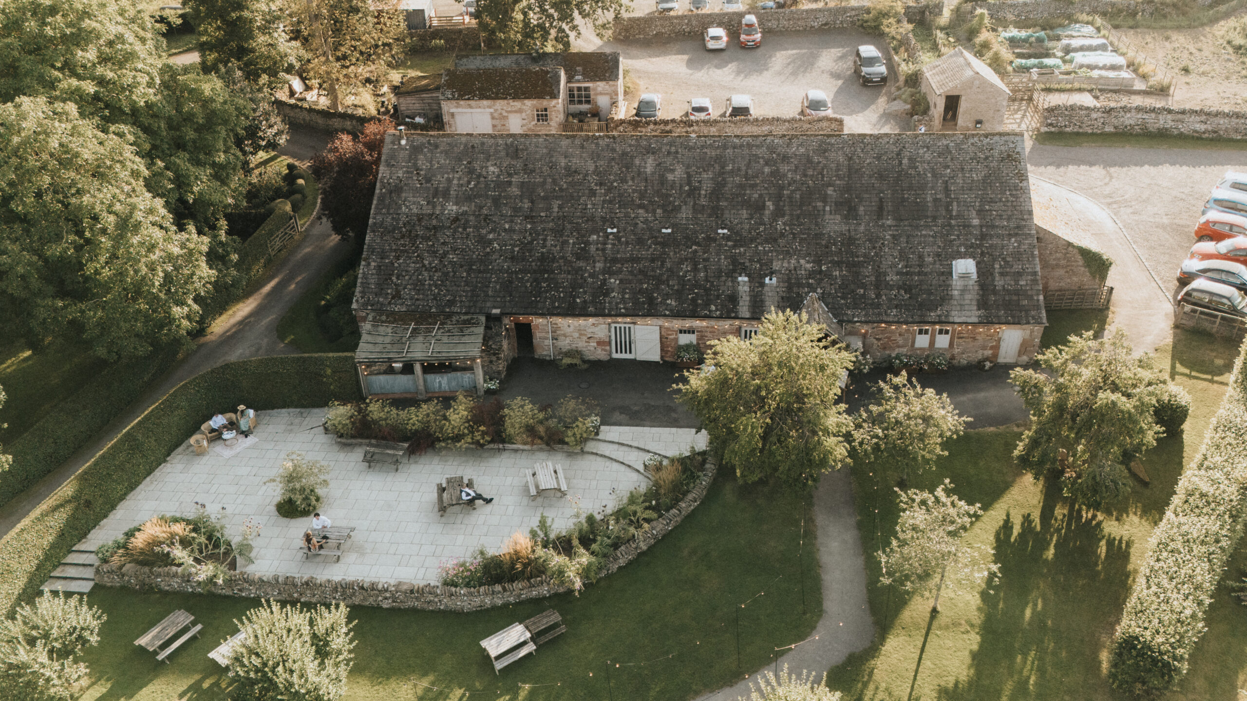 Bank Barn from above, with its paved terrace, lawn and car park, Askham Hall