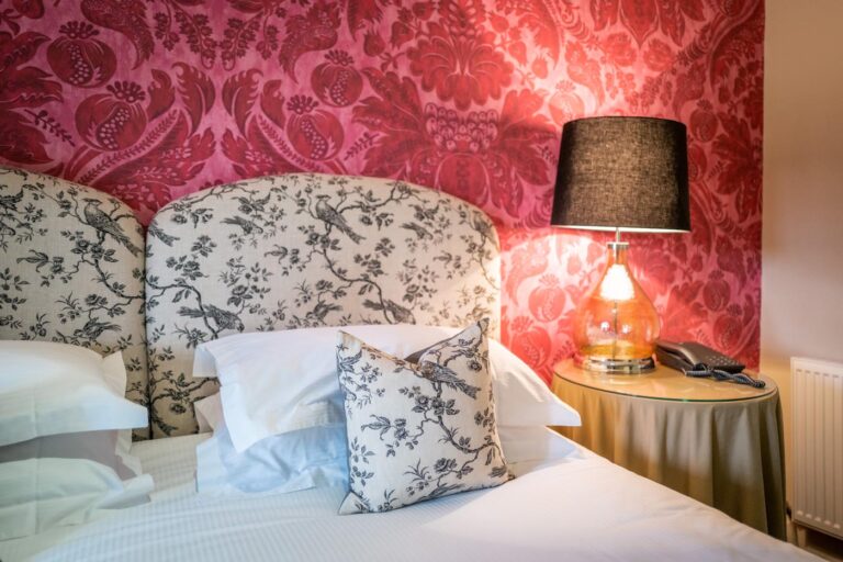 Cherry, a bedroom with red damask walls and bird-print upholstered headboards, Askham Hall