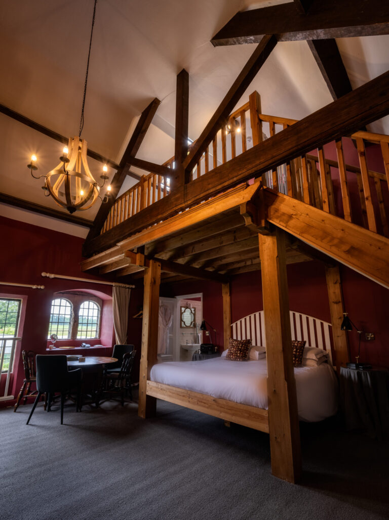 The Train Room, a double-height bedroom with a timber mezzanine above the bed, Askham Hall