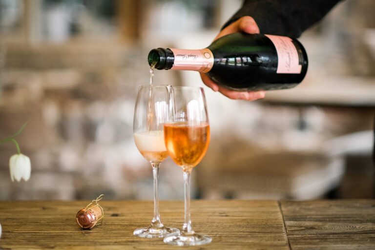 Rose Champagne poured into two glasses on a wooden table, Askham Hall