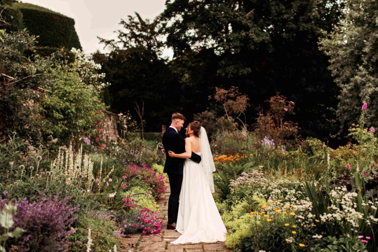 A couple on a stone path through the summer borders in the gardens, Askham Hall