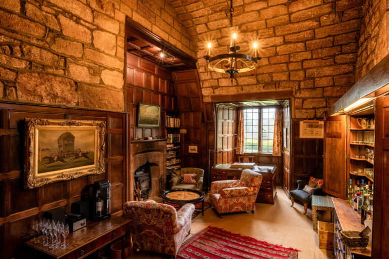 The Stone Room, with panelling, a log burner, bookshelves and the honesty bar, Askham Hall