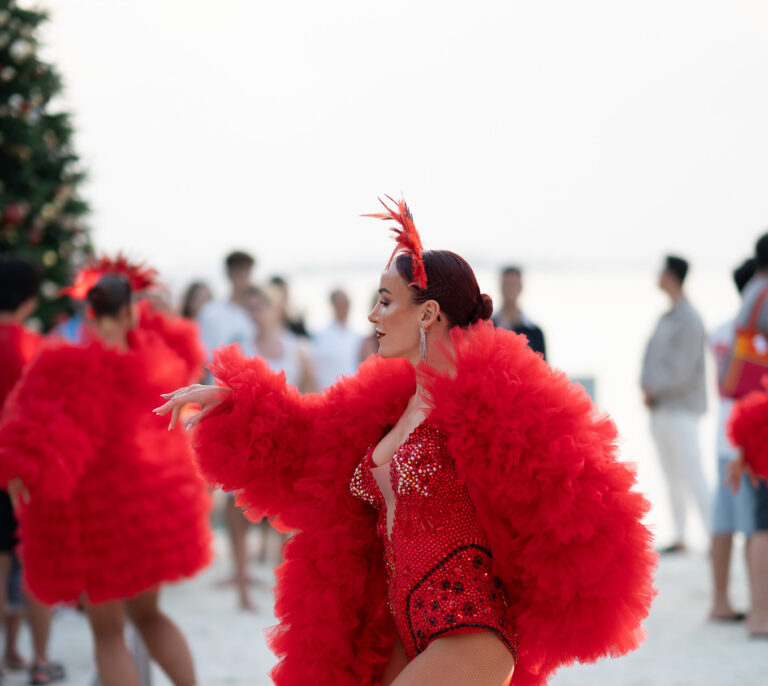 Performers in red feathered costumes entertaining guests outdoors, Aston Band