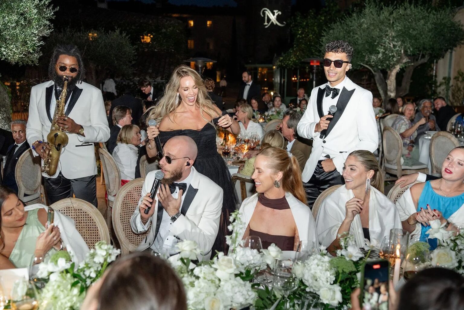 The band performing among the dinner tables at a destination wedding, saxophone and singers on the floor