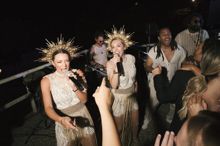 Two vocalists in sunburst crowns performing to guests at a beach club wedding, Capri, Aston Band