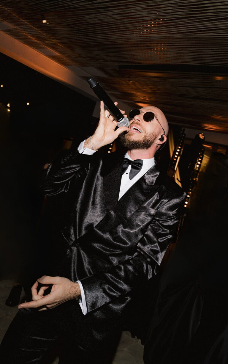 The lead vocalist in a black jacket performing in a dimly lit room, Aston Band