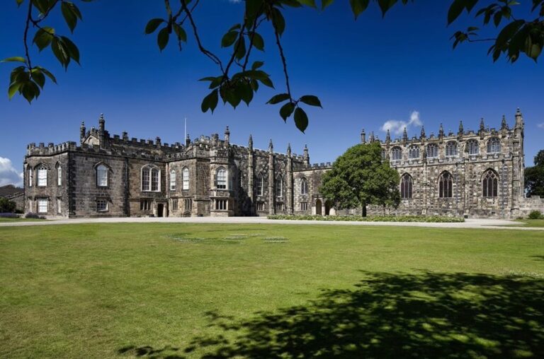 The castle rising from parkland, framed by trees, Auckland Castle