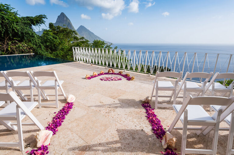 Ceremony chairs and a petal-lined aisle on a poolside terrace with the twin Pitons beyond, Awesome Caribbean Weddings
