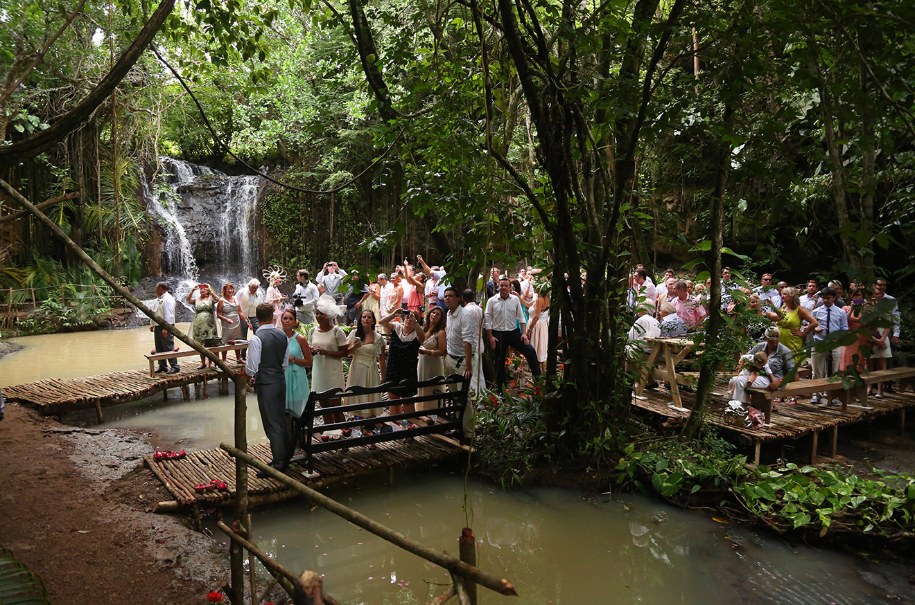 Wedding guests gathered on timber decks beside a waterfall in a tropical forest, Awesome Caribbean Weddings