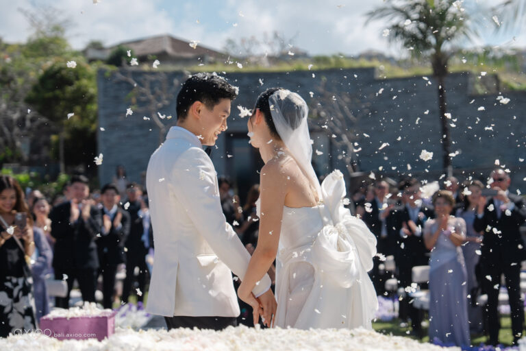 Couple facing each other as petals fall over applauding guests, Bali, Axioo Bali