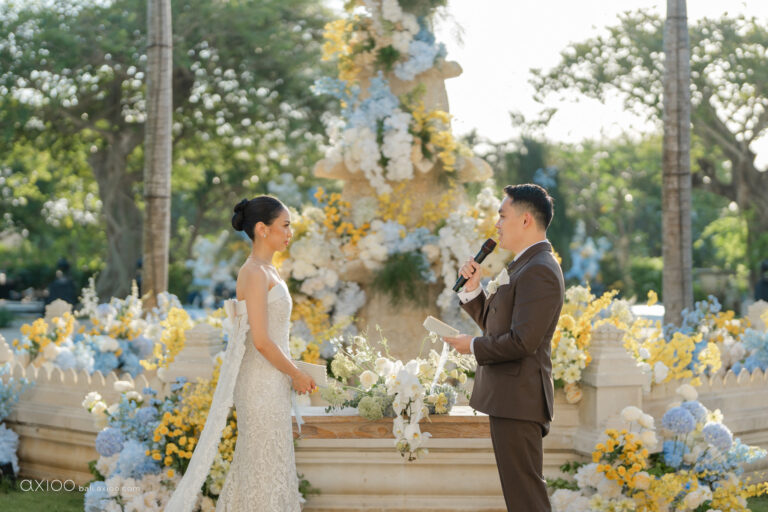 Groom speaking to his bride before a tiered floral installation, Jumeirah Bali, Axioo Bali
