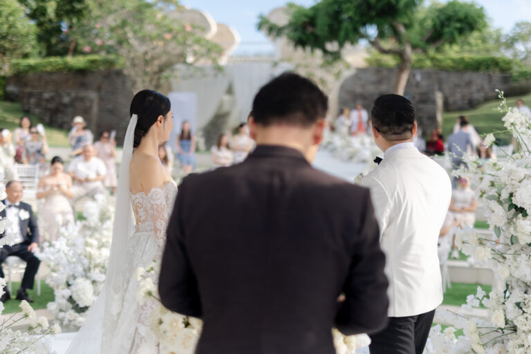 Bride and groom at the ceremony seen from behind the officiant, Bali, Axioo Bali