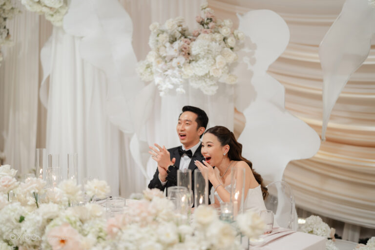 Couple laughing at a floral sweetheart table with draped backdrop, Bali, Axioo Bali